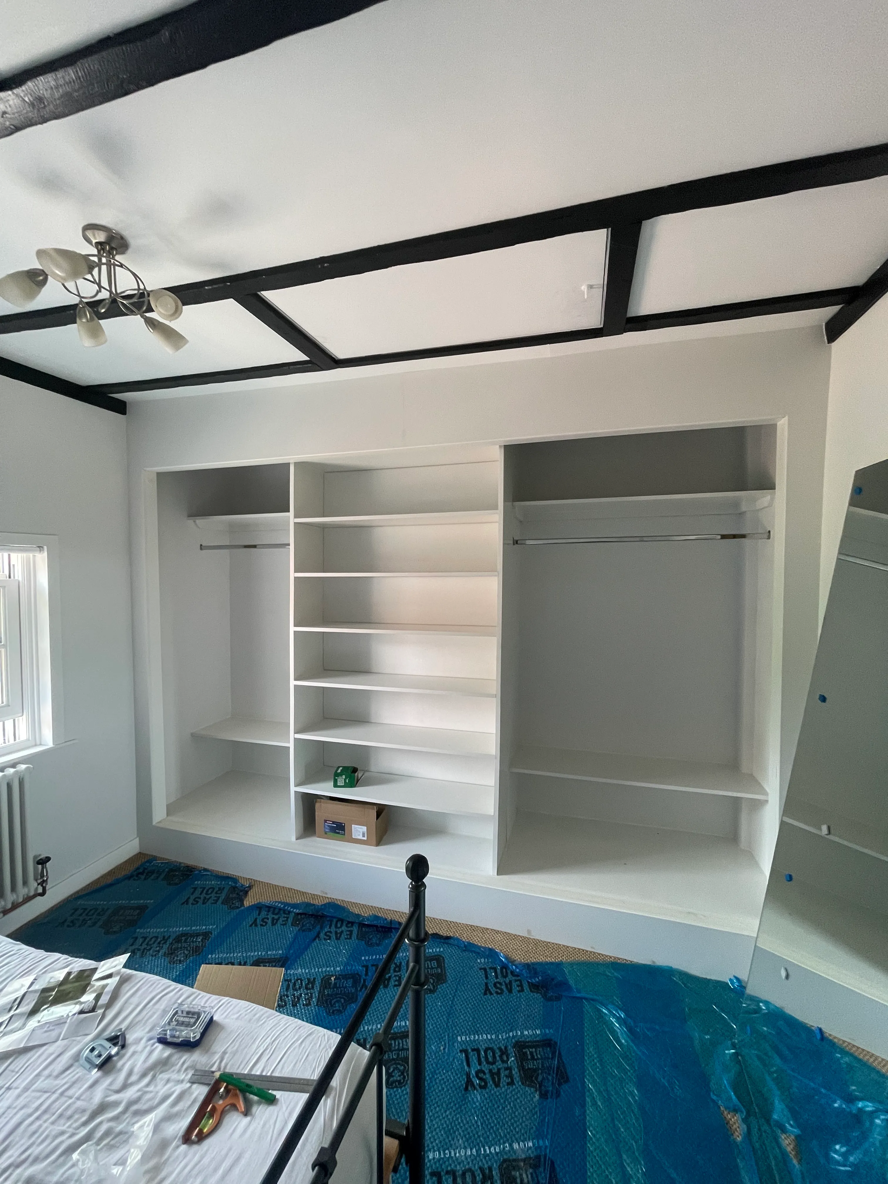 Painted built-in joinery with vertical plate rack alongside the sliding wardrobe.