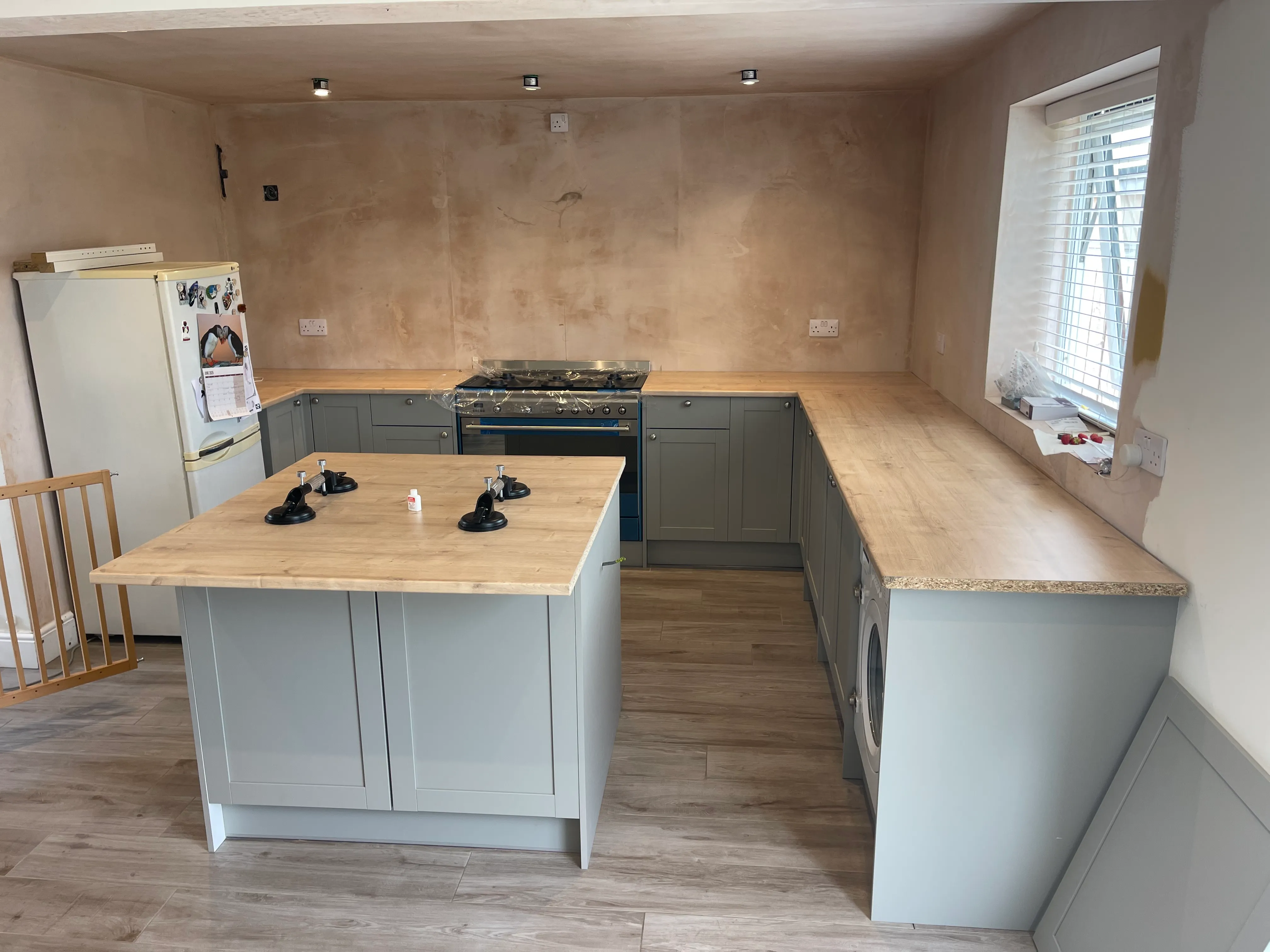 Soft-grey shaker kitchen with oak worktop, central island, and range cooker.