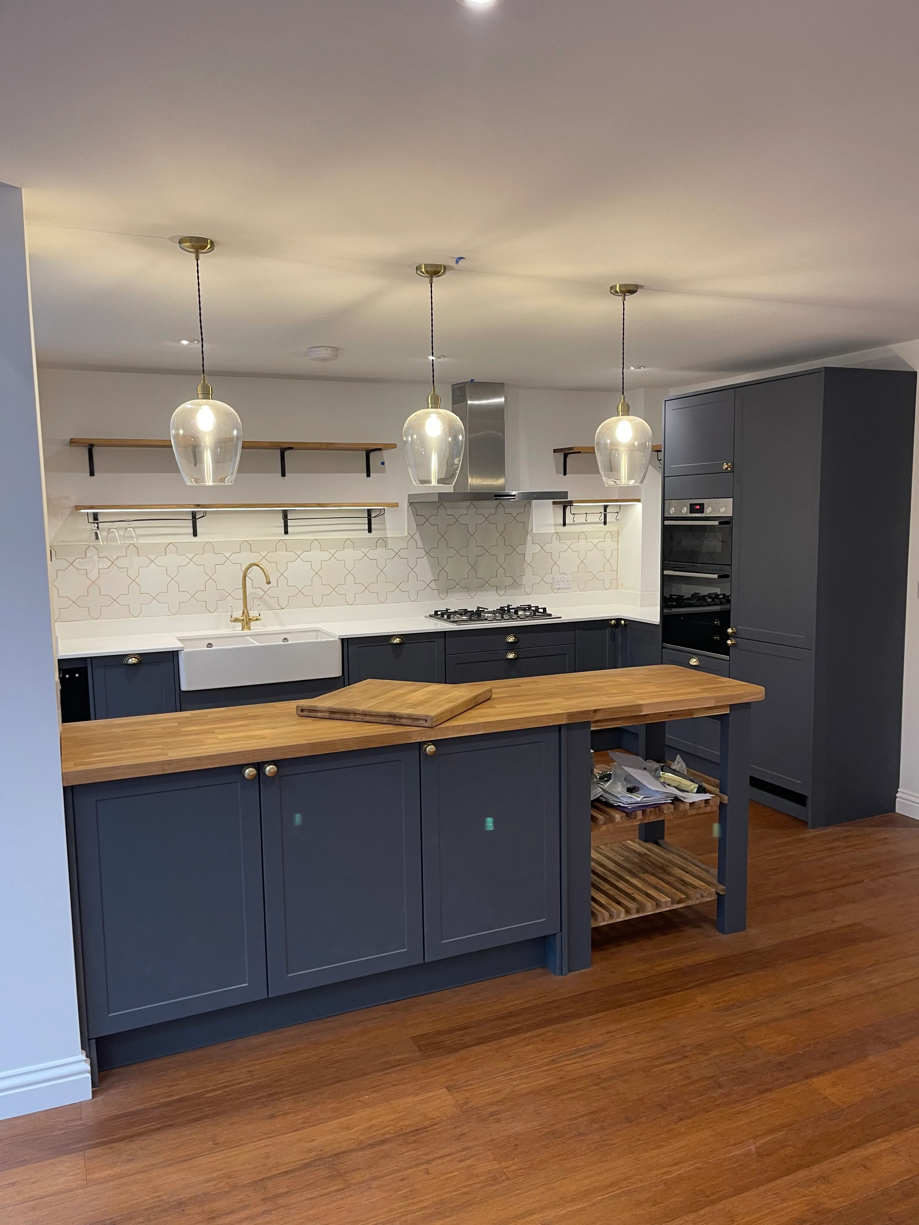 Navy shaker island with brass pendants and a Moroccan tile splashback.