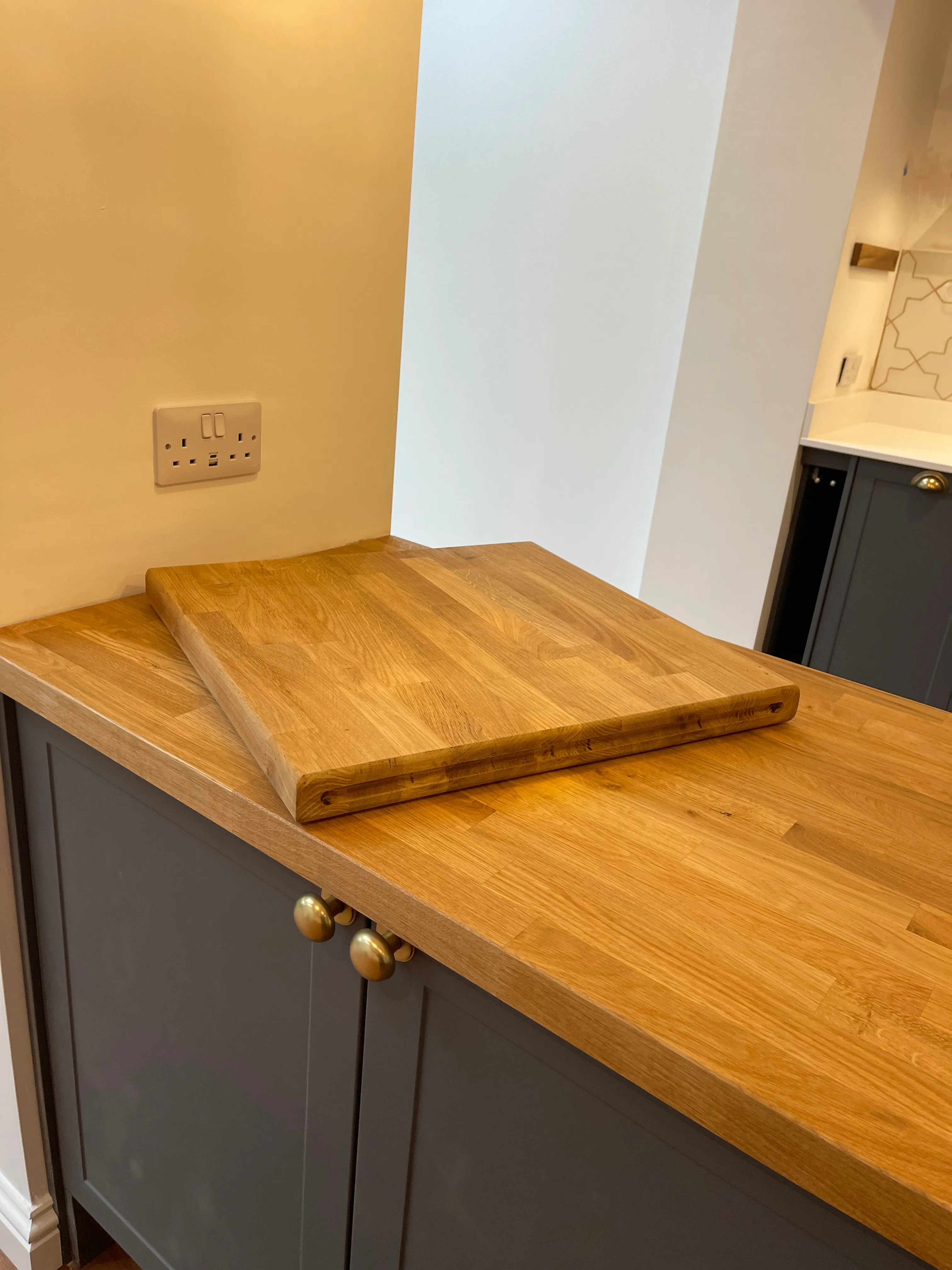Solid oak waterfall breakfast bar on a navy shaker island with brass cup handles.