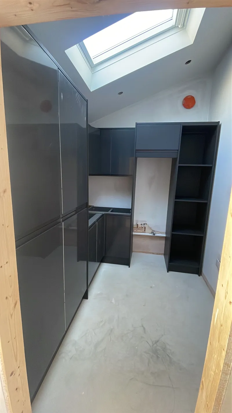 Bespoke utility room with black painted under-counter storage and exposed beams.