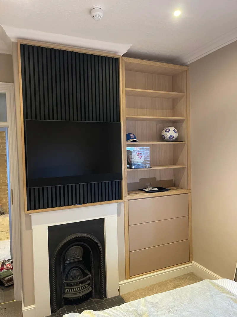 Oak media wall with integrated plate rack and blush-pink base cupboards.
