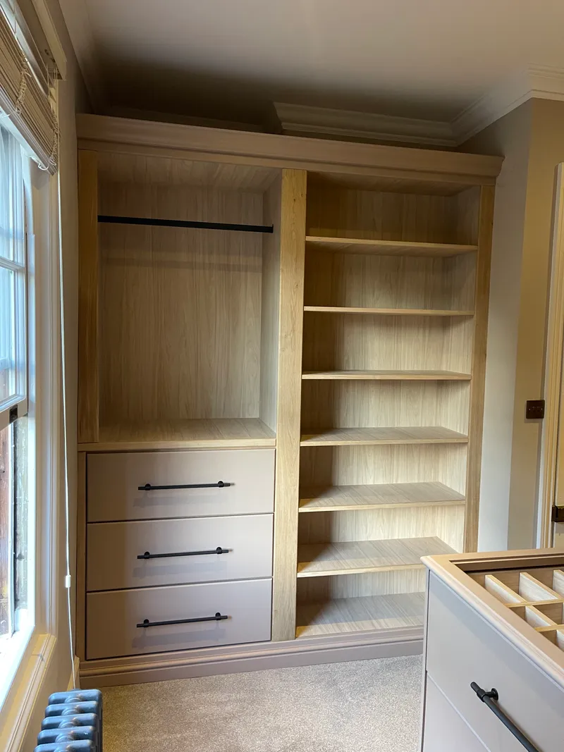 Bespoke walk-in wardrobe with full-height storage and bronze bar handles.